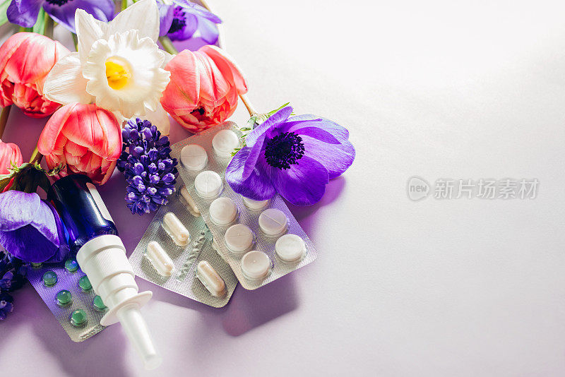 季节性春季过敏。抗组胺药和鼻喷雾剂平铺着紫红色的花朵。过敏护理