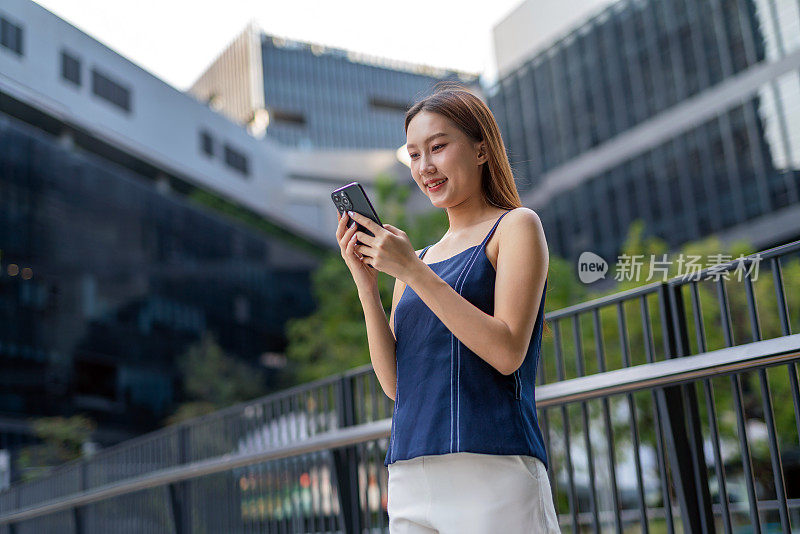 年轻的亚洲女性在移动中使用手机，在户外无缝地利用无线技术