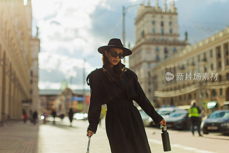 穿着黑色外套的女人在城市里散步。街头风格