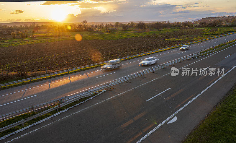 汽车在公路上高速行驶，穿过乡村风景。高速公路高速行驶。高速公路上超速行驶的景象。背景是美丽的日落。