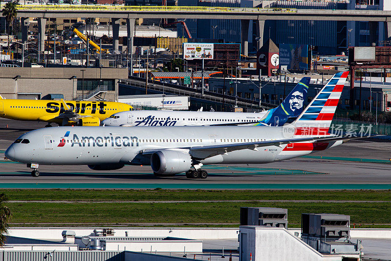 一架美国航空公司的空客波音787-9梦幻客机在洛杉矶国际机场滑行，背景是精神航空公司和阿拉斯加航空公司的飞机
