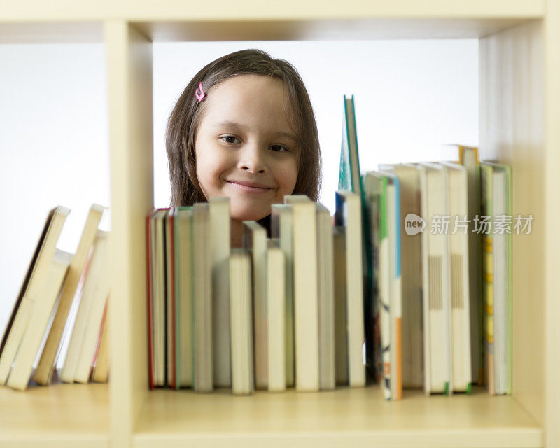 年轻的女孩在看书架上的书