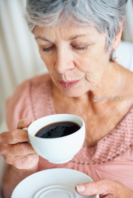 一个高级女士吹凉的空气在她的茶杯的特写