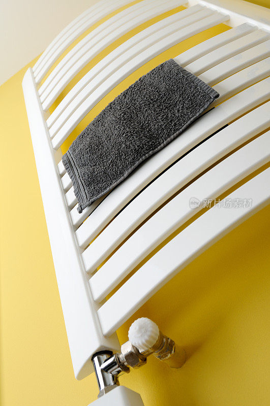 浴室加热器，毛巾散热器在黄色的墙上