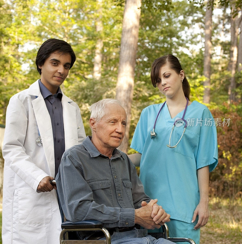 医生、护士和病人坐在轮椅上享受外面的天气