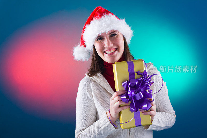 快乐的女人戴着圣诞帽拿着礼物