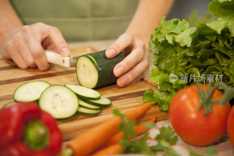 女人在家庭厨房里切黄瓜，蔬菜。沙拉。