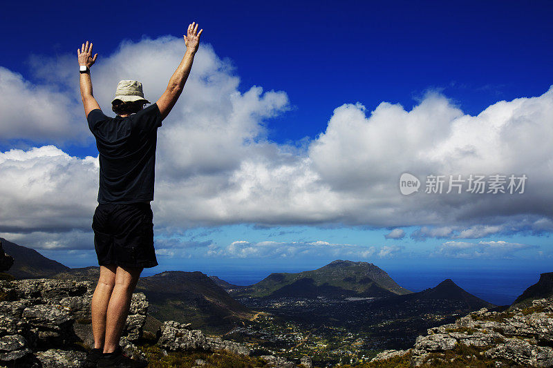 徒步旅行者在山顶举起他的手