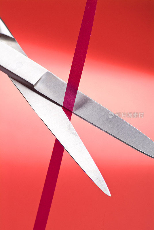 剪刀剪出一条红色的带子，红色的背景。