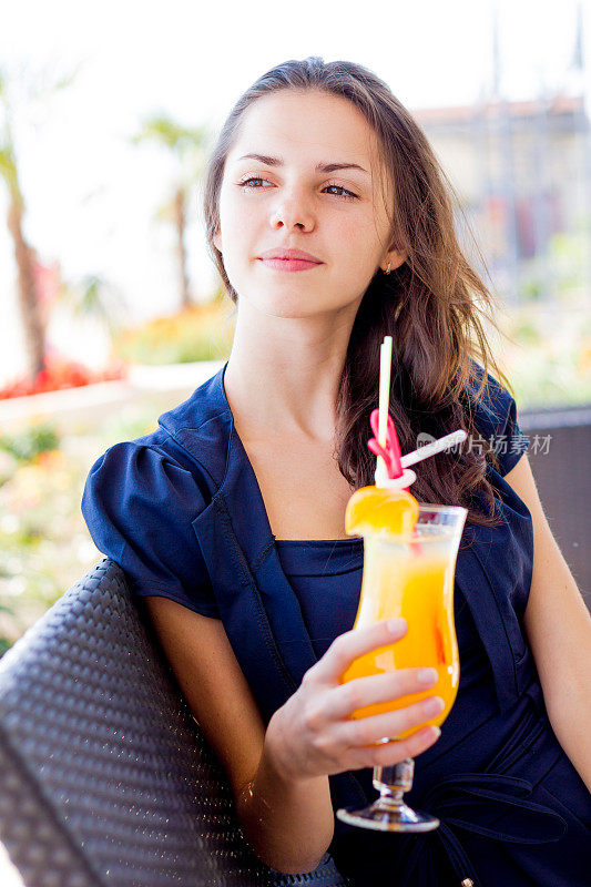 一个年轻女子在夏日的咖啡馆里拿着一杯橙汁