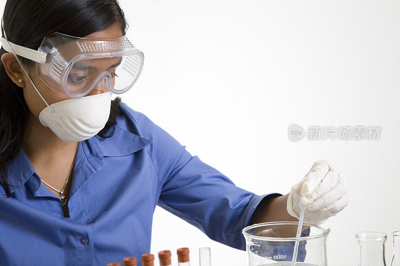 女化验师从烧杯中提取液体样本