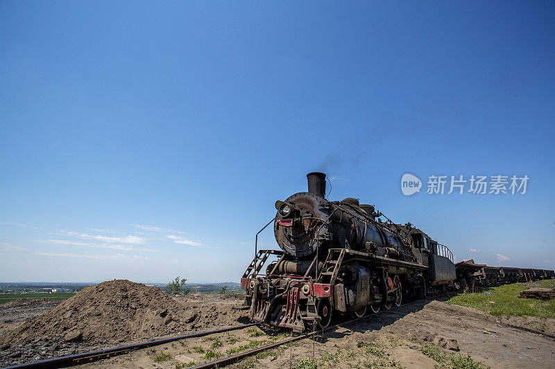 蒸汽火车停在煤山上的铁路上