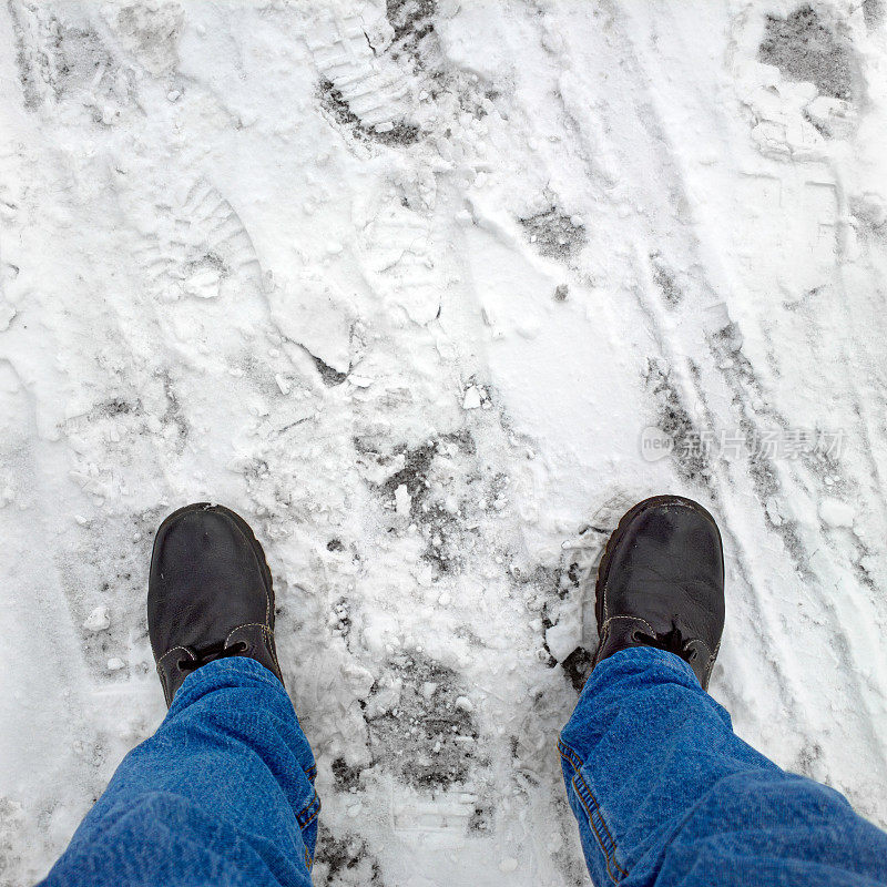 脚踩在雪地里的柏油路上。