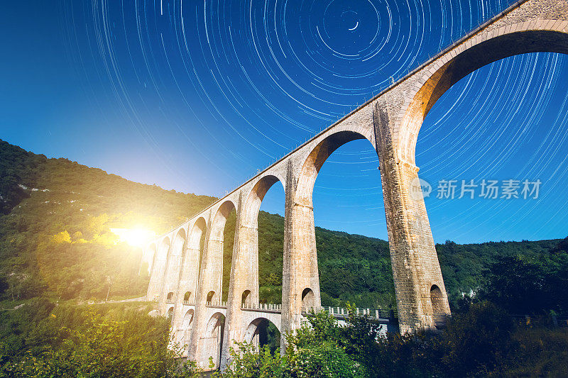 法国古老的石砌拱桥建筑在月光下与星迹在夏夜的天空