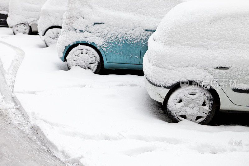 在冬季暴风雪中停放的被雪覆盖的汽车