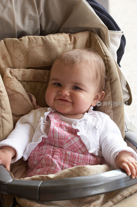 可爱的10个月大的女孩在婴儿车