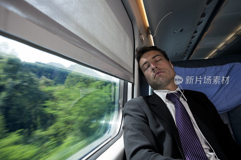 一个商人坐在火车上靠窗休息，边听音乐边休息