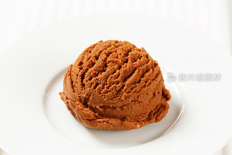 一勺巧克力冰淇淋放在白盘子里