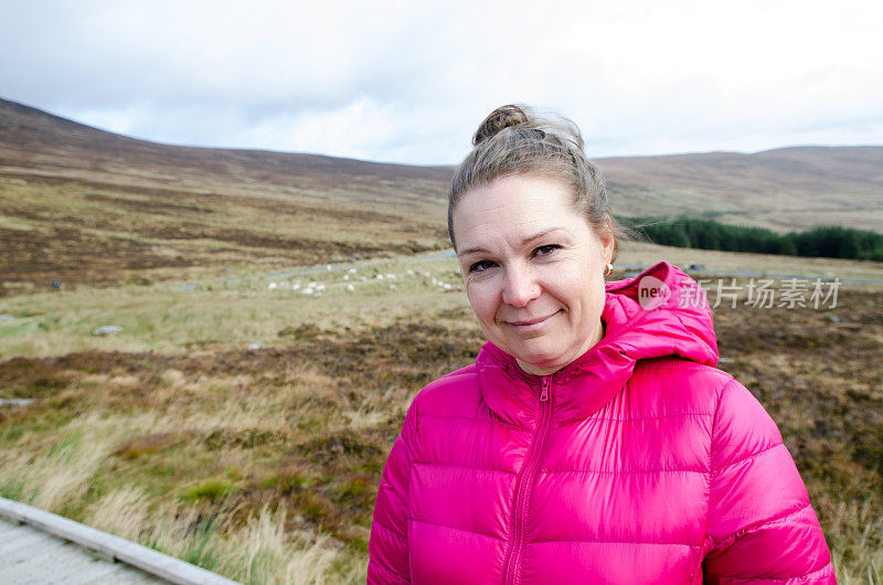 一名女子在爱尔兰威克洛山脉前摆姿势，背景是绵羊