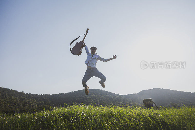 年轻有权势的男人拿着吉他在球场上跳来跳去