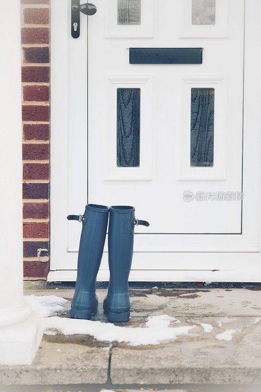 在英国牛津郡的一个下雪天，一双威灵顿长筒靴站在前门