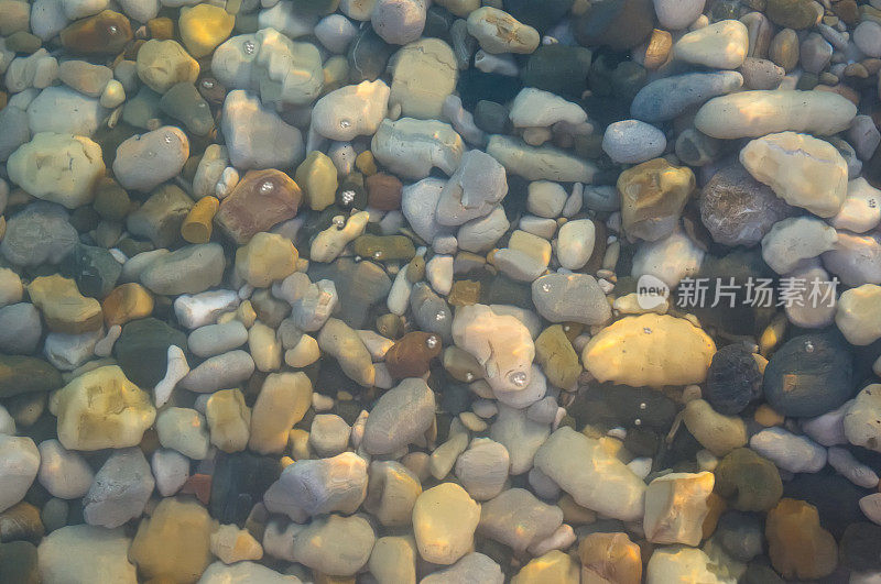 海卵石滩上有五颜六色的石头，浪花上有泡沫