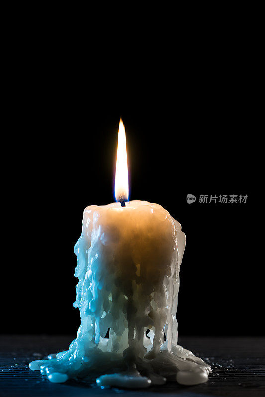 燃烧的蜡烛。光的火焰和流动的蜡烛蜡，黑暗的背景