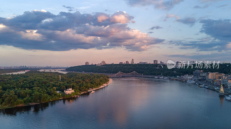 从上面鸟瞰基辅城市，山丘，步行公园桥和日落的第聂伯河，乌克兰