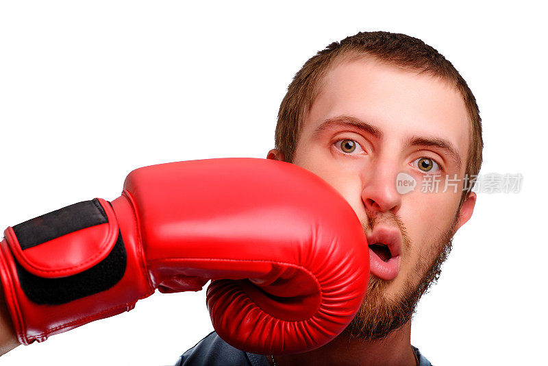 一个年轻的拳击手对着镜头摆姿势。男人的脸被红色拳击手套打了一拳