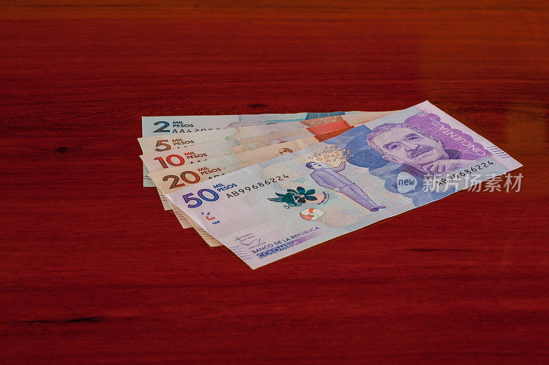南美哥伦比亚-新哥伦比亚钞票在红木桌上呈扇形排列。副本的空间。