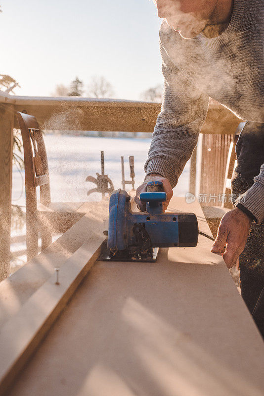 在寒冷的冬天，人们在室外锯木头，做木工