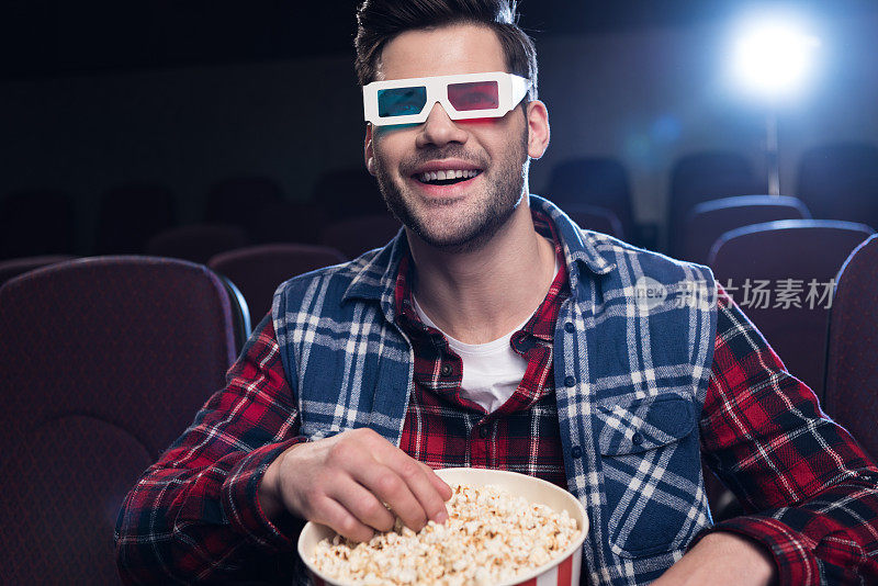 戴着3d眼镜，带着爆米花在电影院看电影的男人
