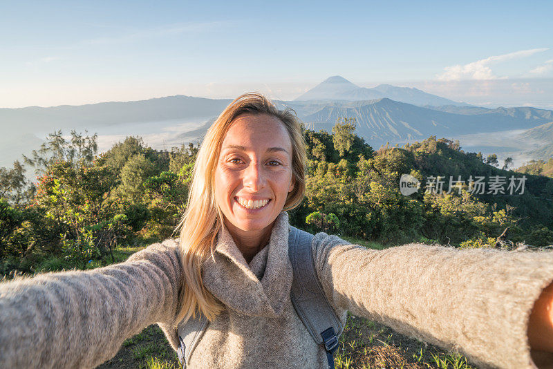 年轻女子徒步与火山自拍