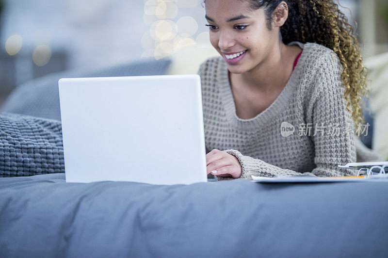 非裔美国少女在床上用笔记本电脑