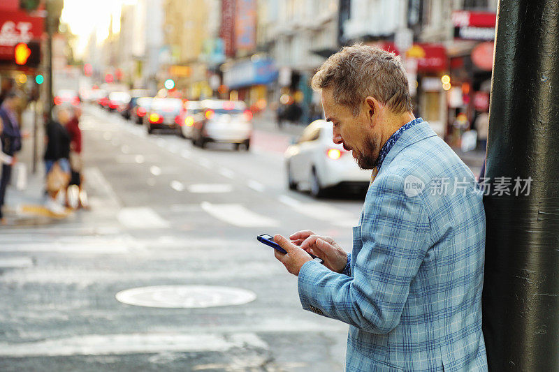 一个成熟的商人在旧金山市中心用手机订拼车