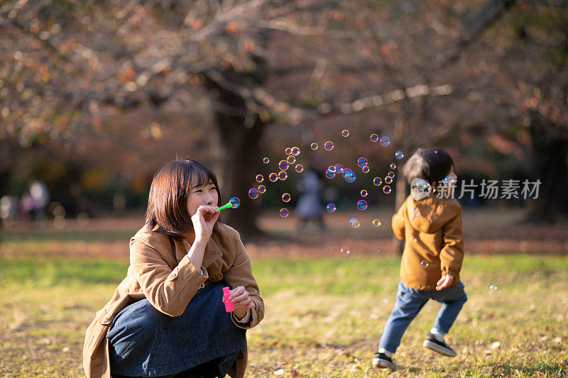 年轻的母亲和儿子在公园里玩肥皂泡