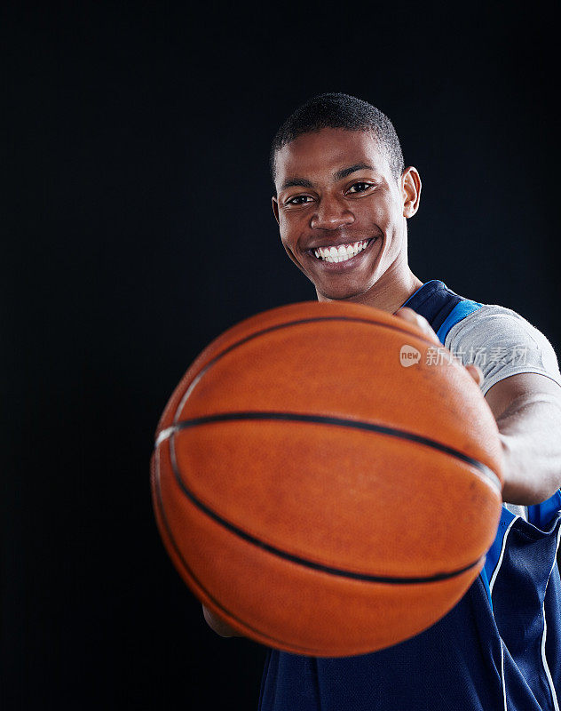 年轻的篮球运动员微笑着拿着球对着镜头