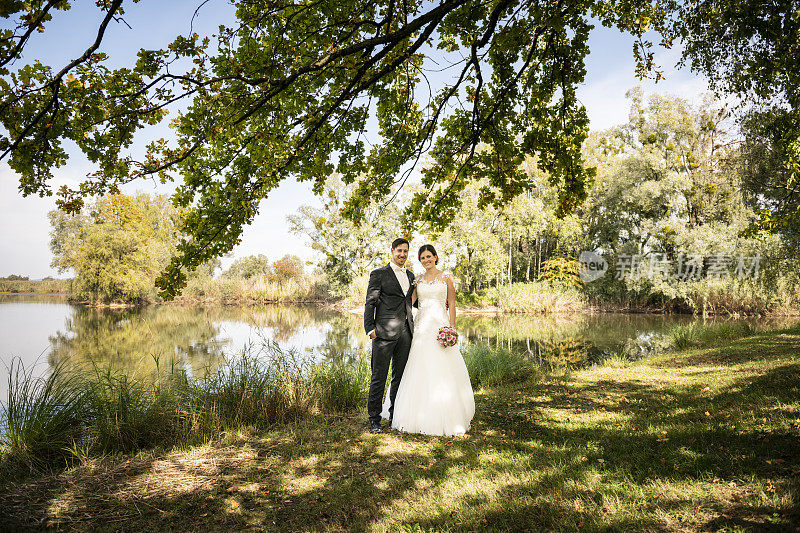 刚刚结婚的新娘和新郎站在湖边
