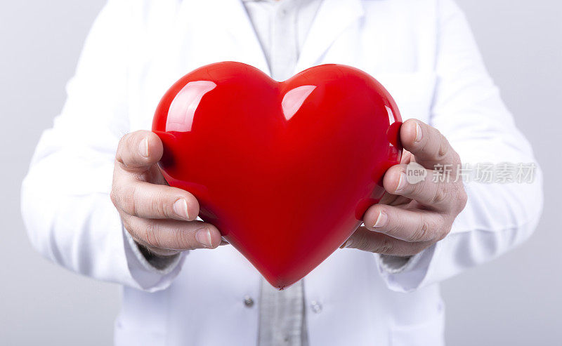 男医生怀里抱着心脏。医学中的保健和心脏病学概念