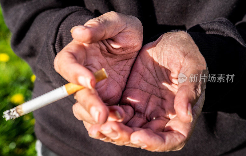 无家可归的女人手里拿着香烟乞讨