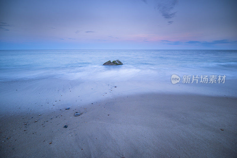 美丽的日落在岩石海岸。在汹涌的波浪中运动。