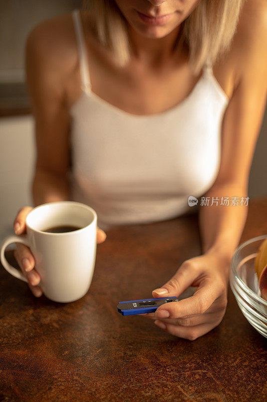 年轻女子拿着验孕棒喝着咖啡