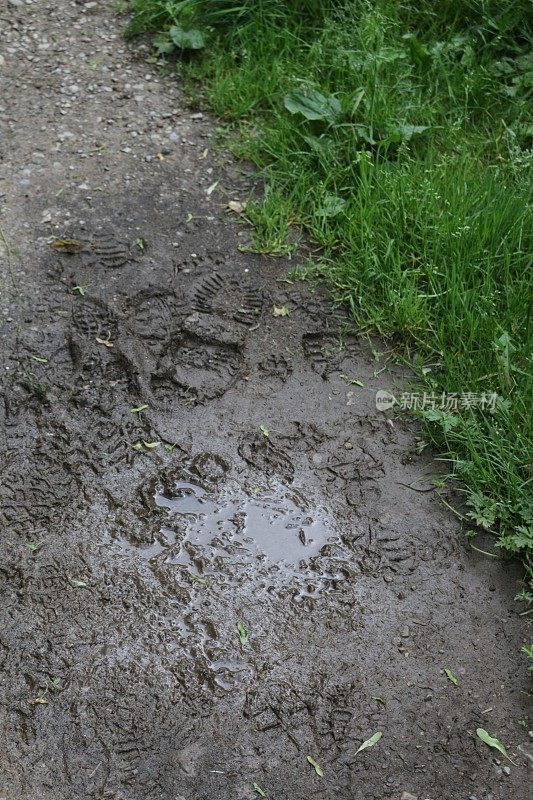 倾盆大雨过后，被水浸透的乡间小路上满是水坑，泥泞的靴子和脚印留在泥泞中