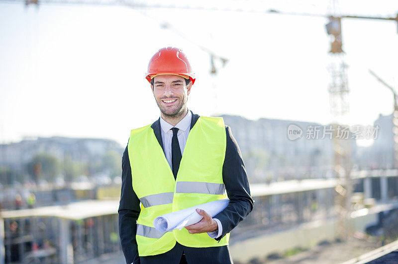 年轻的建筑工程师带着工程和安全帽