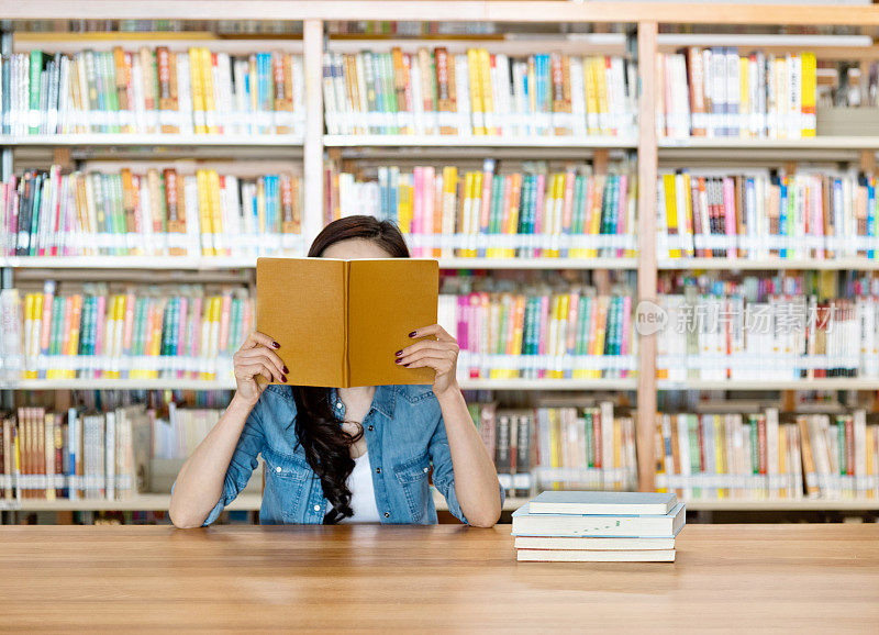 躲在图书馆里一本书后面的女人