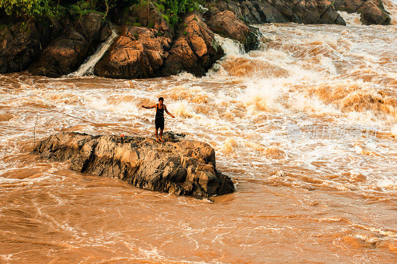 老挝渔民在湄公河上撒网捕鱼。