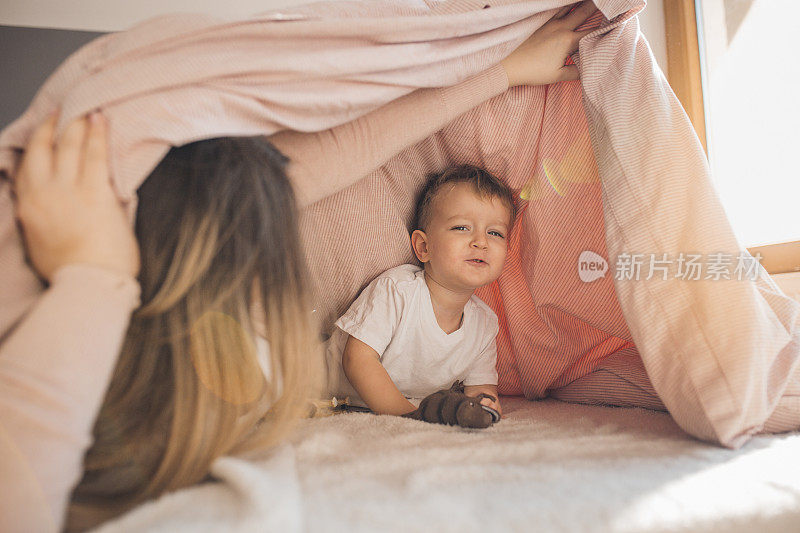 怀孕的妈妈和年幼的儿子在卧室里玩耍