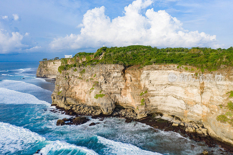 Uluwatu巴厘岛。蓝色的海洋和岩石山，覆盖着热带树木。