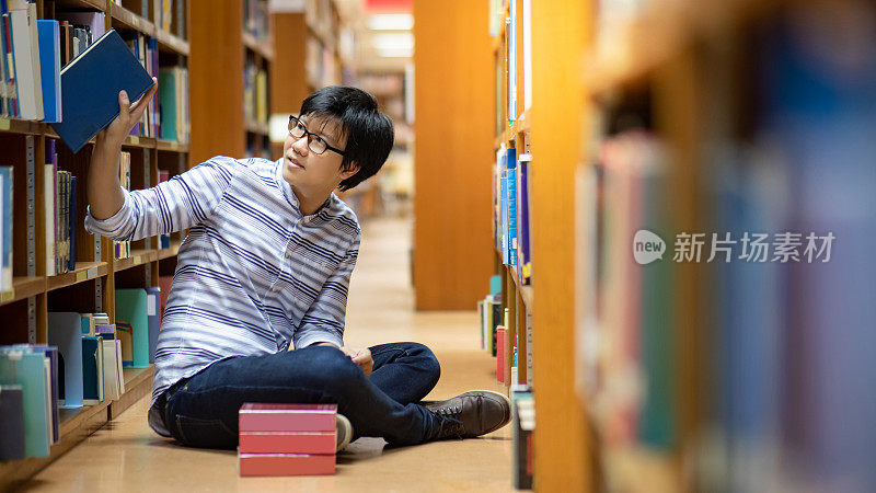 聪明的亚洲人学生在图书馆看书