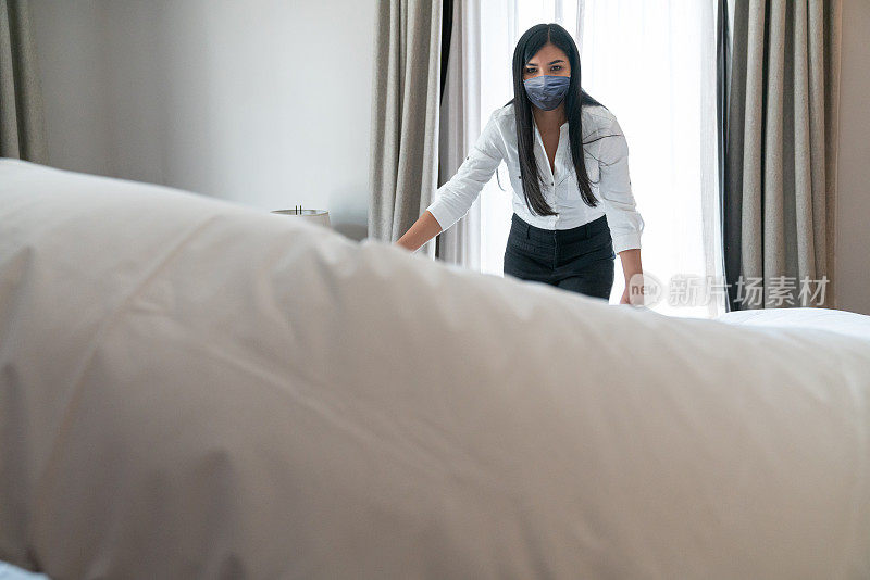 一个拉丁女佣的肖像戴着防护面具，在酒店房间里戴着面具